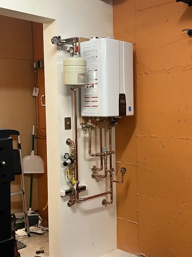 Plumbing technician inspecting water heater connections in Vandergrift